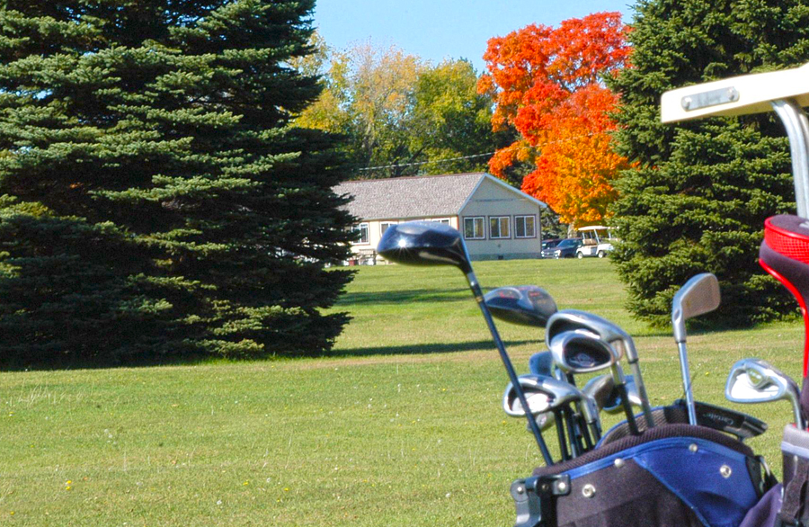 Hole 7 fairway at Nahma Golf Club with the clubhouse and fall colors.